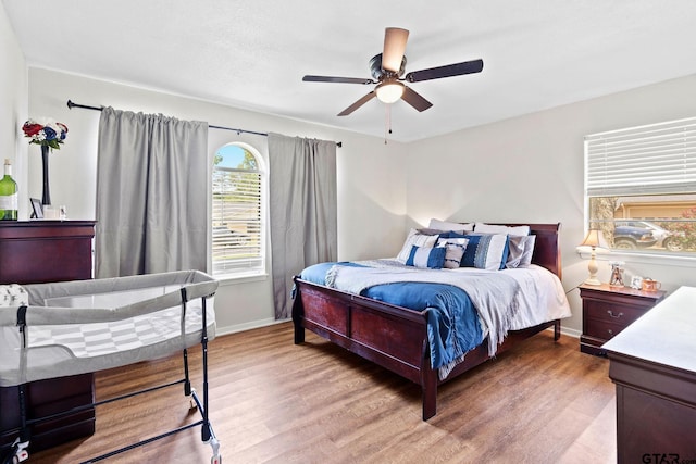 bedroom with light wood finished floors, baseboards, and a ceiling fan