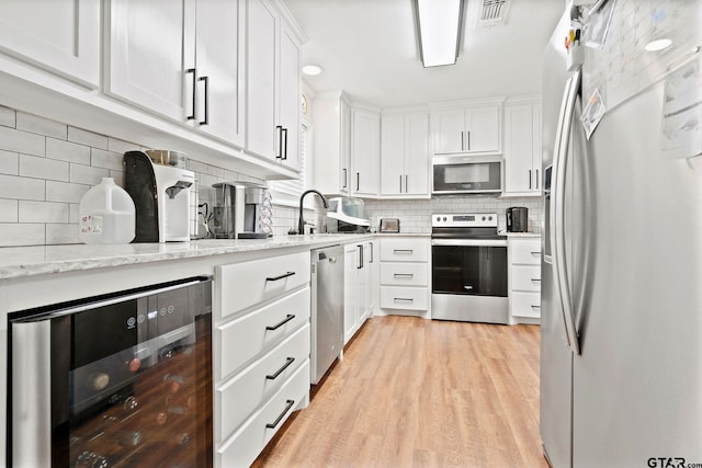kitchen featuring beverage cooler, white cabinetry, stainless steel appliances, and a sink