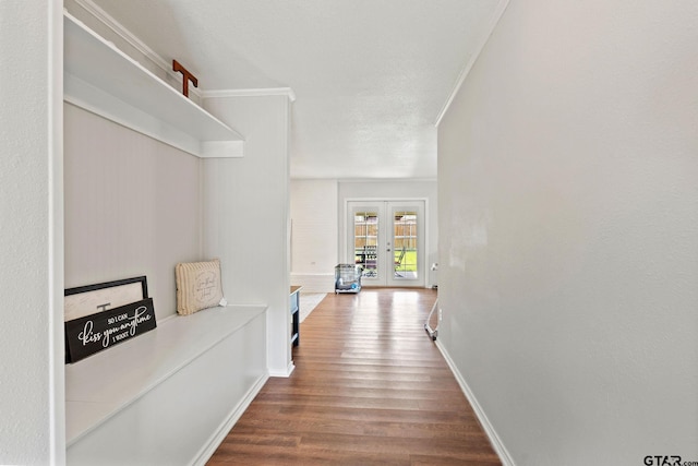 corridor with wood finished floors, crown molding, and baseboards