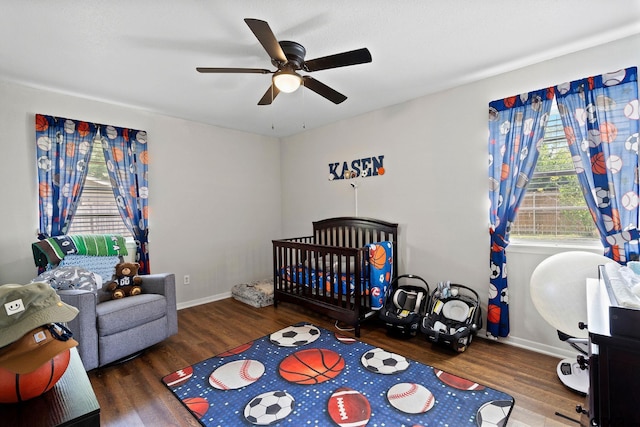 bedroom with a crib, baseboards, and wood finished floors