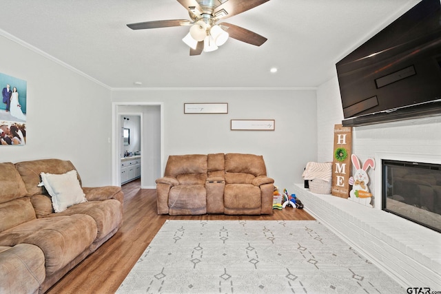living room with recessed lighting, wood finished floors, crown molding, a fireplace, and ceiling fan
