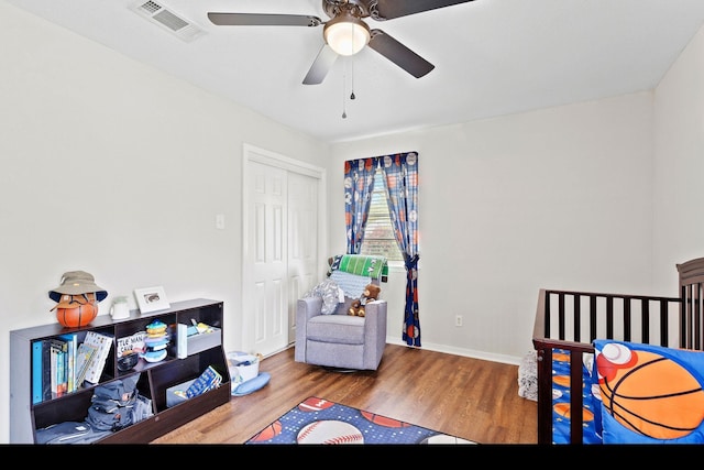 bedroom featuring wood finished floors, a closet, ceiling fan, baseboards, and visible vents