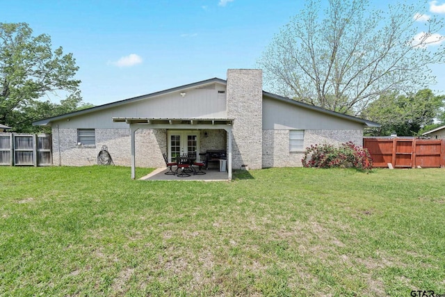 rear view of property with a lawn, a patio, fence private yard, and french doors