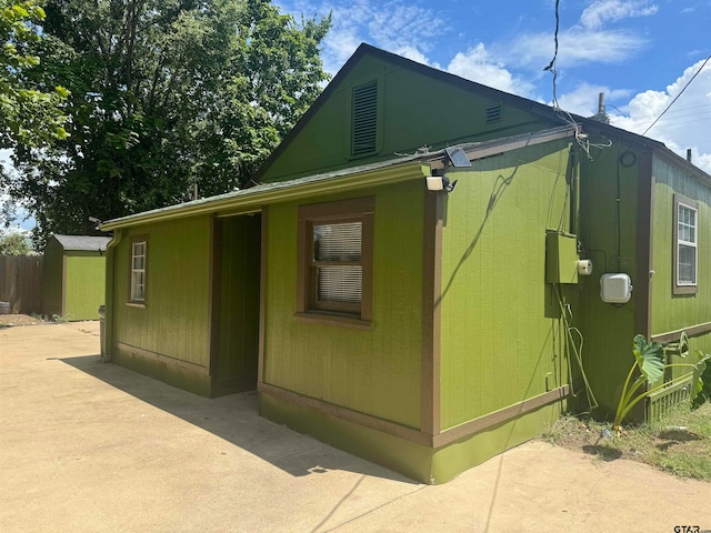 view of home's exterior with a shed and a patio