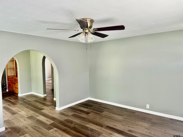 empty room featuring dark wood-type flooring, ceiling fan, and a textured ceiling