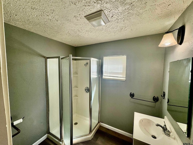 bathroom featuring vanity, an enclosed shower, and a textured ceiling