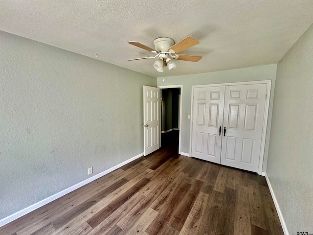 unfurnished bedroom featuring dark wood-type flooring, ceiling fan, a textured ceiling, and a closet