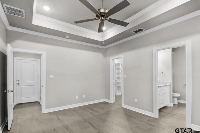 unfurnished bedroom with a spacious closet, ceiling fan, ensuite bathroom, and ornamental molding