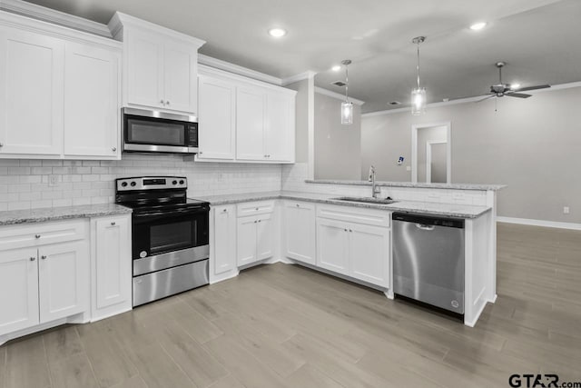 kitchen with kitchen peninsula, appliances with stainless steel finishes, ceiling fan, sink, and white cabinets