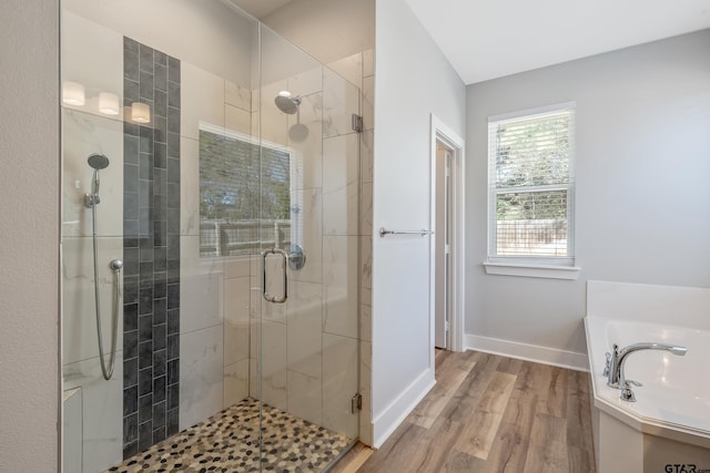 full bathroom with a stall shower, wood finished floors, baseboards, and a bath