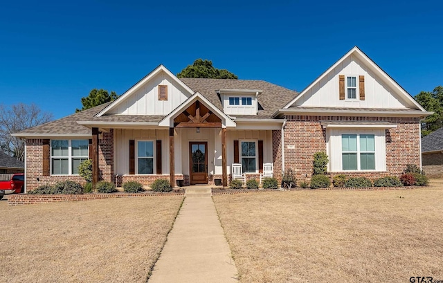 view of front of property featuring a shingled roof, a front lawn, and brick siding