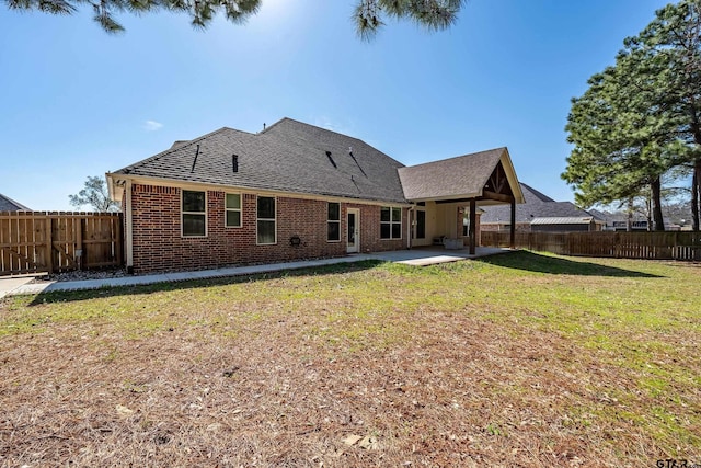 back of property with a yard, brick siding, and a fenced backyard