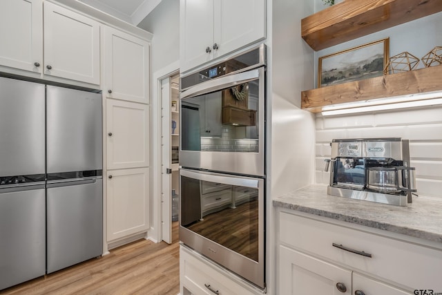 kitchen featuring stainless steel appliances, light wood finished floors, and white cabinets