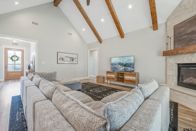 living room featuring high vaulted ceiling, a fireplace, wood finished floors, and visible vents