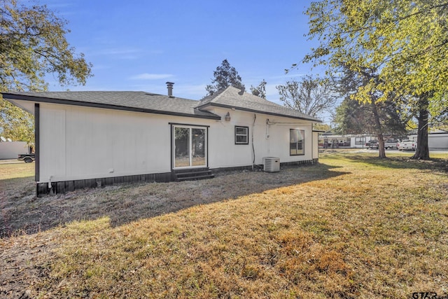 rear view of house featuring central AC and a yard