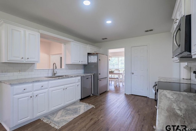 kitchen with black microwave, stainless steel dishwasher, high quality fridge, a sink, and white cabinetry
