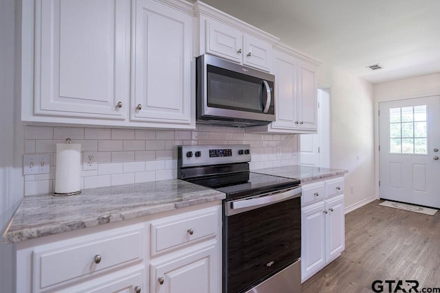 kitchen with backsplash, stainless steel appliances, visible vents, and white cabinetry