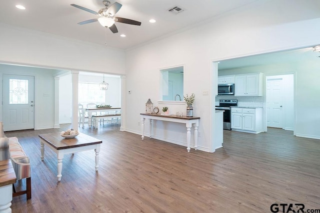 living room featuring a ceiling fan, crown molding, wood finished floors, baseboards, and recessed lighting