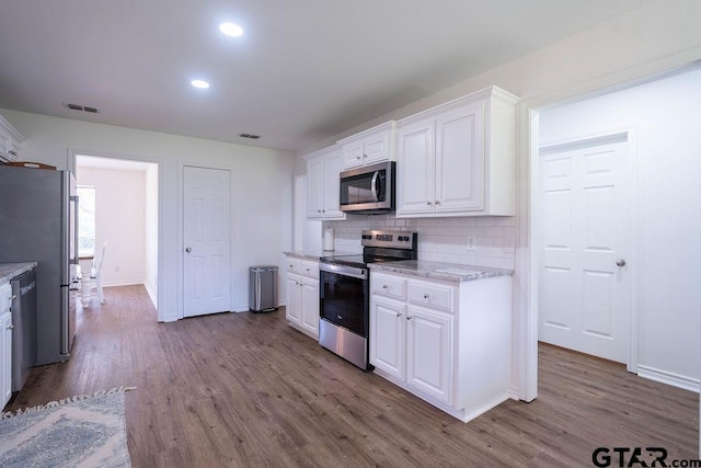 kitchen with white cabinets, stainless steel appliances, visible vents, and wood finished floors