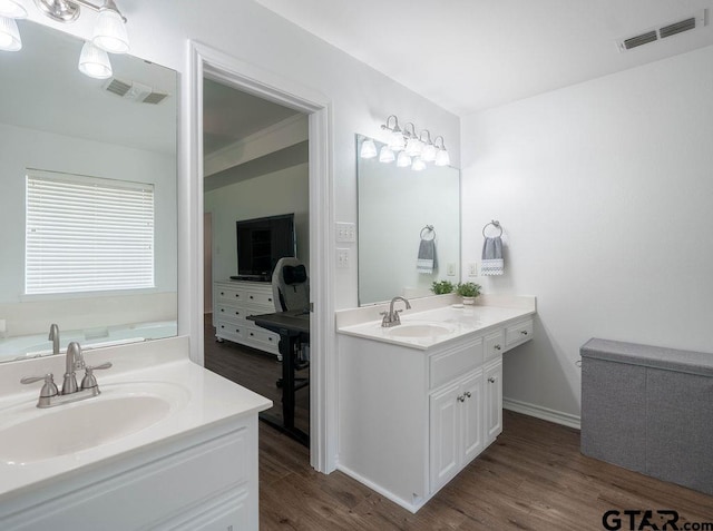 full bathroom with visible vents, two vanities, a sink, and wood finished floors