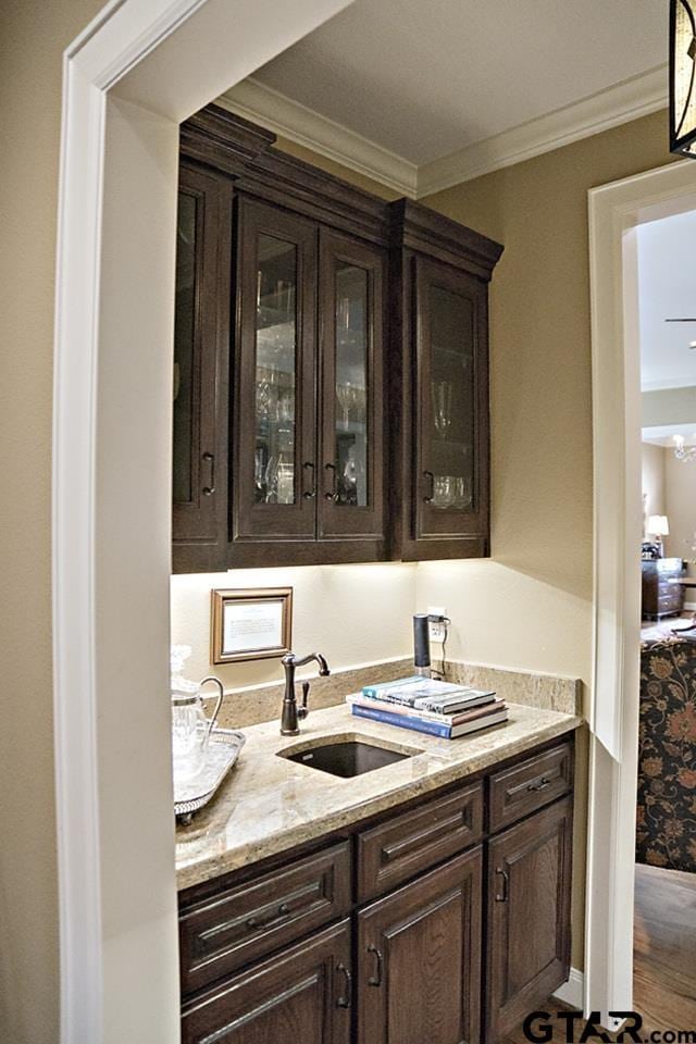 bar featuring ornamental molding, wood finished floors, and a sink