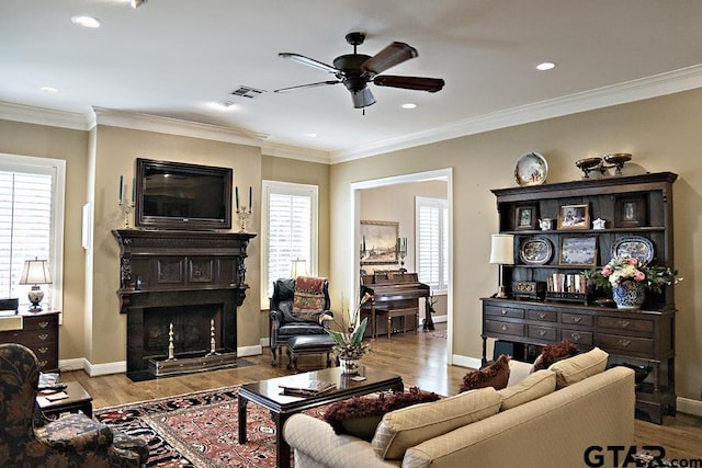 living area featuring visible vents, wood finished floors, ornamental molding, and a fireplace with flush hearth