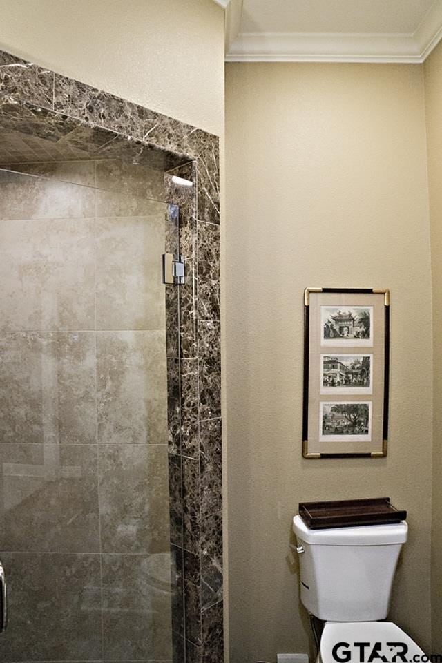 full bath featuring a stall shower, toilet, and crown molding