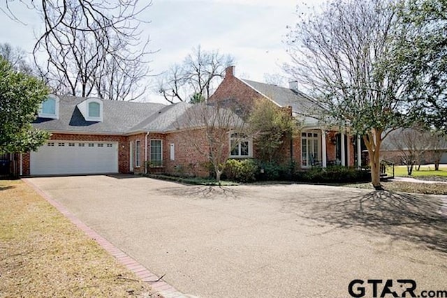 view of front of home with brick siding, an attached garage, and driveway