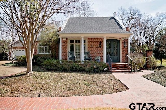 bungalow-style house with french doors, brick siding, and a chimney