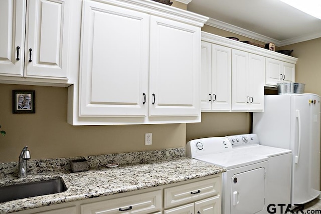 clothes washing area featuring a sink, cabinet space, ornamental molding, and washer and dryer