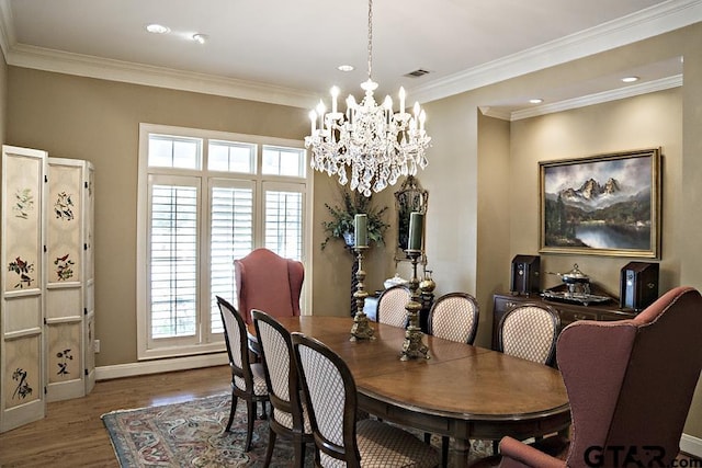 dining area featuring visible vents, a notable chandelier, wood finished floors, crown molding, and baseboards