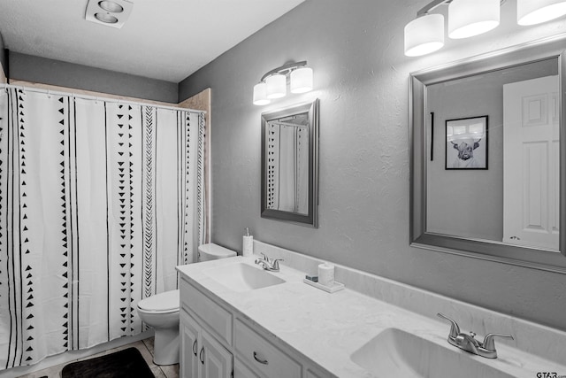 bathroom with tile patterned floors, vanity, toilet, and curtained shower