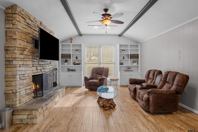 living room with vaulted ceiling with beams, light hardwood / wood-style flooring, ceiling fan, and a stone fireplace