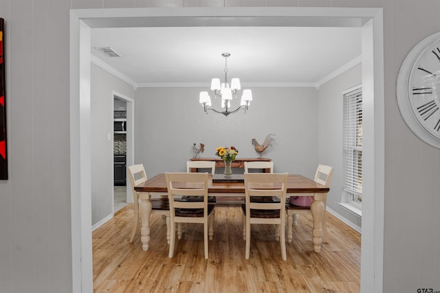 dining room with light hardwood / wood-style floors, crown molding, wooden walls, and a chandelier