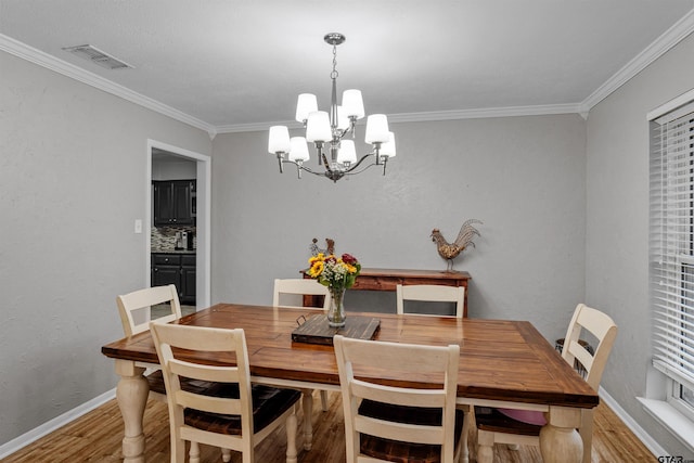 dining space featuring light hardwood / wood-style flooring, an inviting chandelier, and ornamental molding