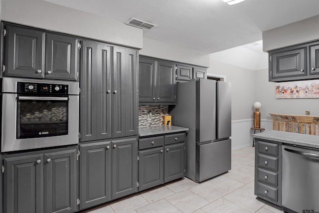 kitchen with appliances with stainless steel finishes, tasteful backsplash, and gray cabinetry