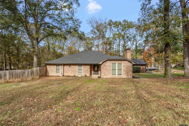 ranch-style house with a front lawn, a chimney, fence, and brick siding