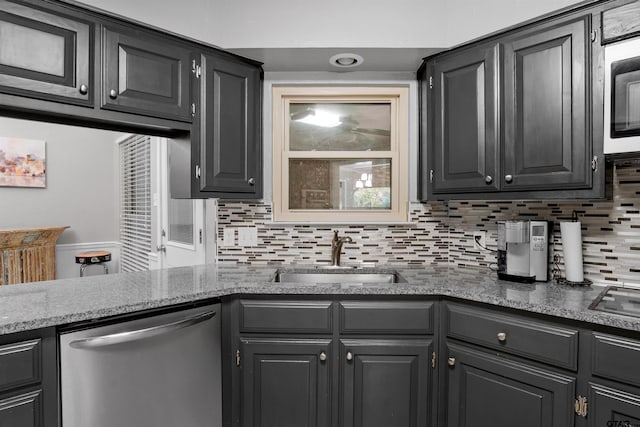 kitchen featuring backsplash, sink, stone countertops, and appliances with stainless steel finishes