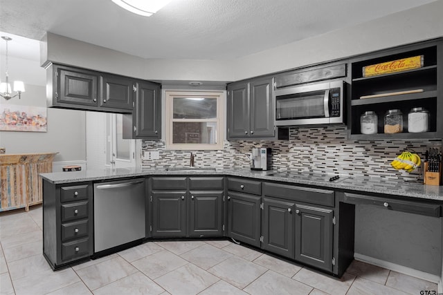 kitchen featuring appliances with stainless steel finishes, decorative light fixtures, dark stone counters, and sink