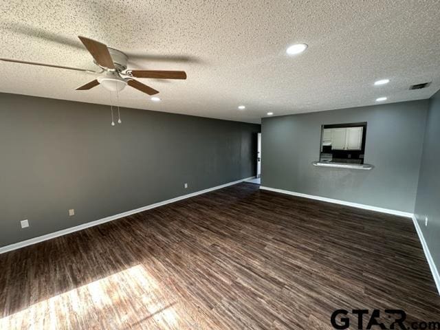 spare room with dark wood-style floors, visible vents, baseboards, ceiling fan, and a textured ceiling