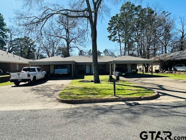 ranch-style home featuring an attached carport, a front lawn, and driveway