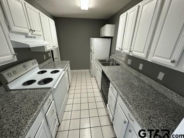 kitchen with under cabinet range hood, a textured ceiling, white appliances, white cabinetry, and a sink