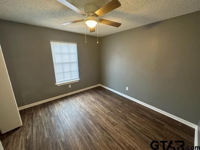 empty room featuring ceiling fan, baseboards, a textured ceiling, and dark wood finished floors