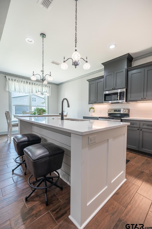 15348 C R 169, Tyler, TX 75703 - kitchen featuring a chandelier, dark wood finished floors, an island with sink, ornamental molding, and light countertops