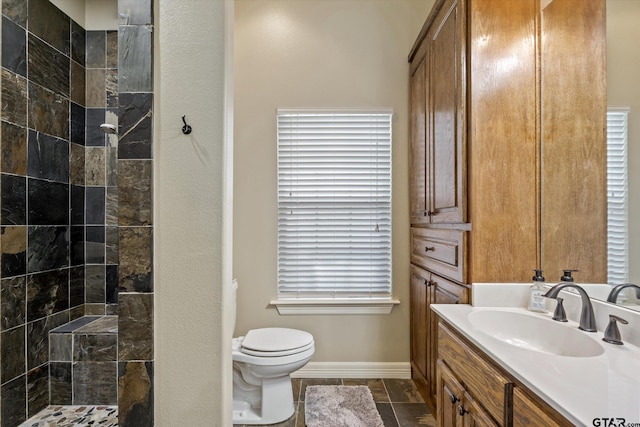 bathroom featuring a tile shower, vanity, and toilet