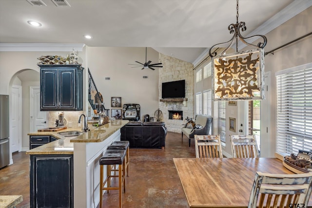 kitchen featuring sink, ceiling fan, crown molding, backsplash, and a fireplace