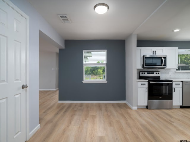 kitchen featuring baseboards, light countertops, white cabinetry, backsplash, and stainless steel appliances