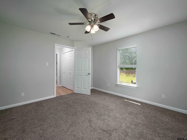 unfurnished bedroom featuring ceiling fan, a closet, visible vents, carpet flooring, and baseboards