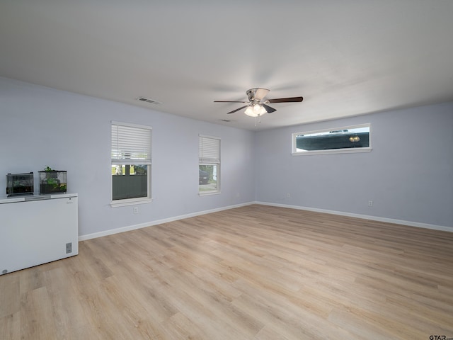 spare room with visible vents, ceiling fan, light wood-type flooring, and baseboards
