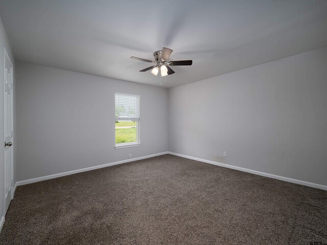 unfurnished room with dark carpet, baseboards, and a ceiling fan
